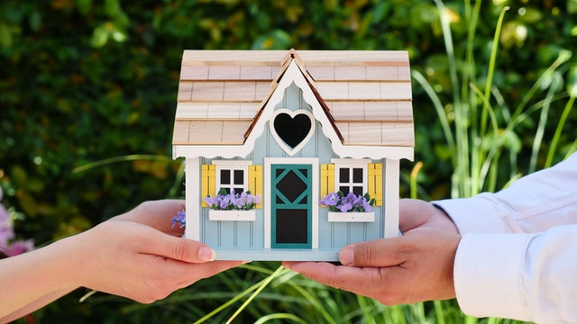 How to Make Your Rental Property More Welcoming for a New Tenant (1) Two people holding a miniature wooden house.